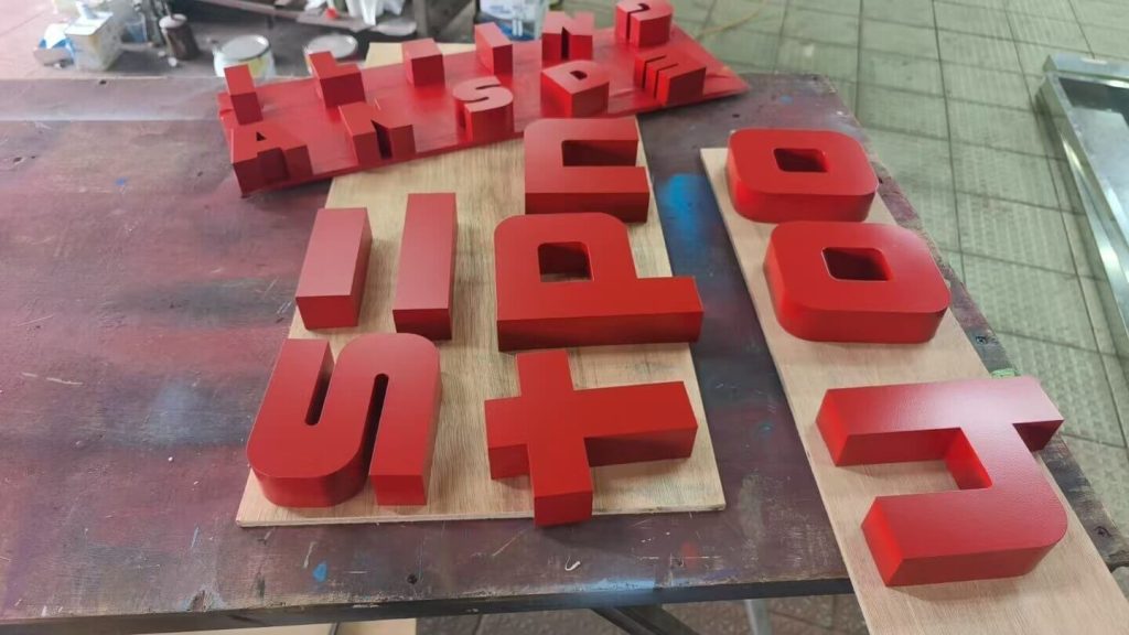 Cut and painted 3D letter parts laid out on the bench in our Guangzhou sign workshop