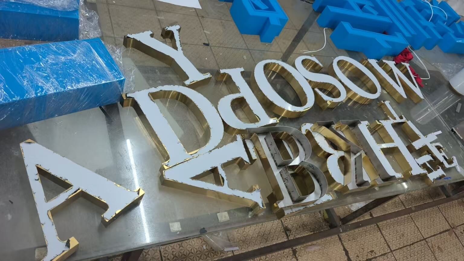 Cut and painted 3D letter parts laid out on the bench in our Guangzhou sign workshop