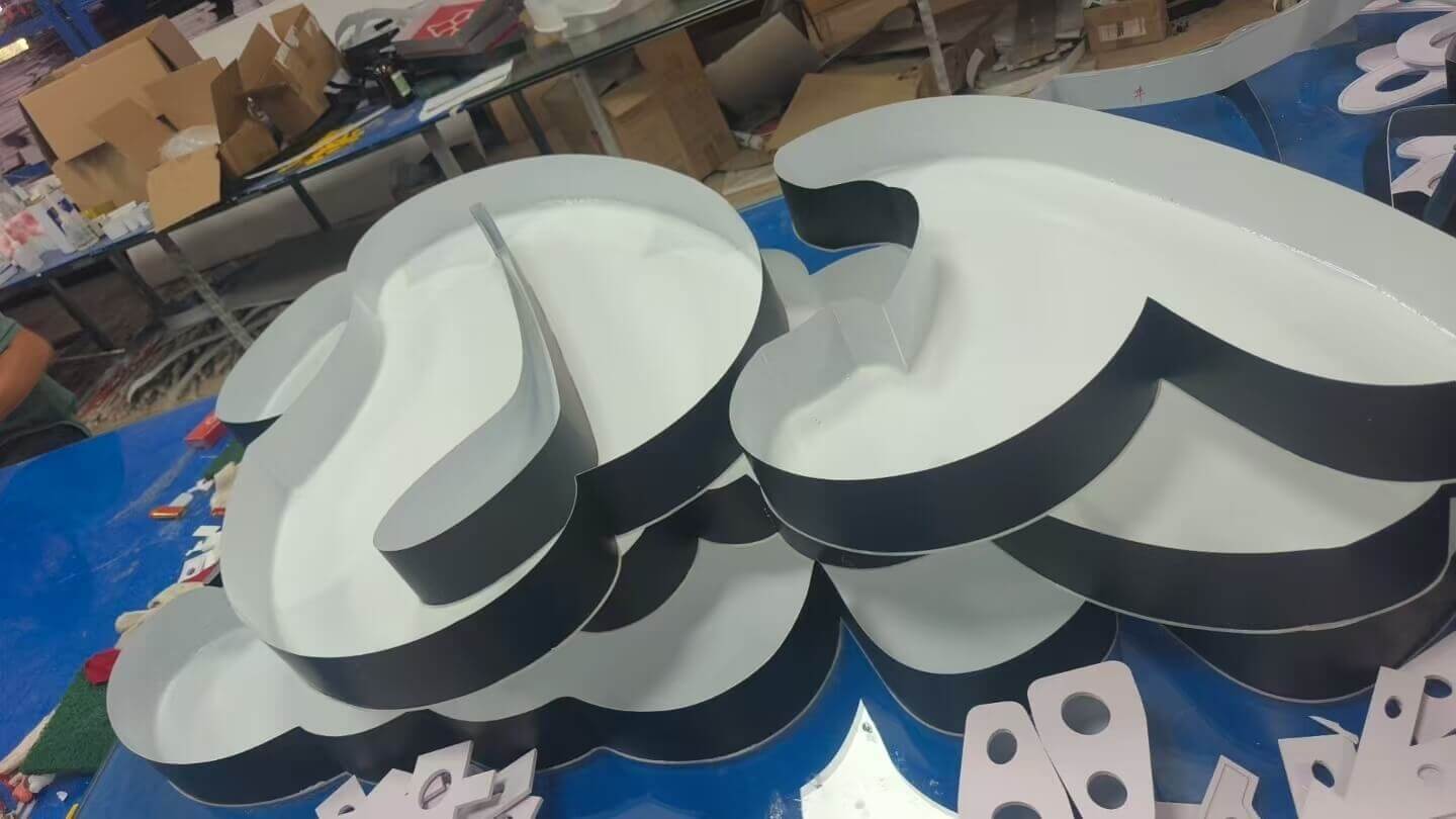 Cut and painted 3D letter parts laid out on the bench in our Guangzhou sign workshop